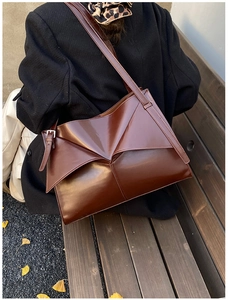 Dettaglio di una borsa tote in pelle verniciata marrone scuro con design geometrico