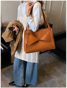 Elegante borsa a spalla in pelle caramello con design a pieghe in scena lifestyle
