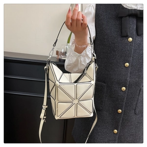 Detailed view of cream geometric paneled bucket bag with black stitching and handle