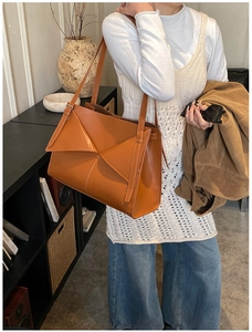 Elegante borsa tote marrone caramello con patta geometrica mostrata in stile street chic