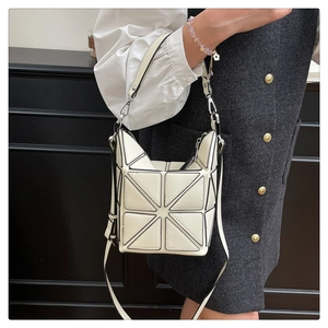 Detail of cream geometric bucket bag with triangle pattern and black contrast edges