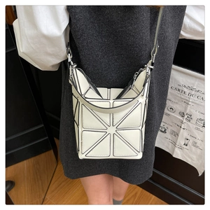 Detail of geometric patchwork bucket bag in beige with black piping for urban style