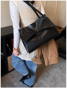 Dettaglio della borsa tote nera con design geometrico a triangolo e finitura opaca