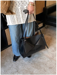 Dettaglio di una borsa tote grande in pelle nera con design geometrico a triangolo