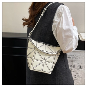 Detail of a minimalist cream bucket bag with geometric patchwork and crossbody strap