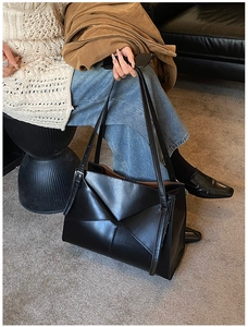 Dettaglio di una borsa tote in pelle nera geometrica con pieghe origami e spalline sottili