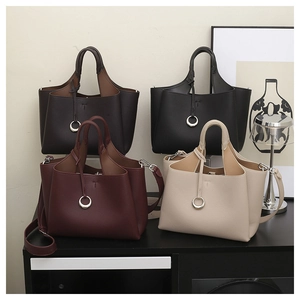 Détail de sacs cabas minimalistes en cuir en quatre couleurs avec logo T et anneau métal