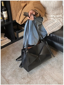 Dettaglio borsa tote minimalista in pelle nera con design geometrico a pieghe