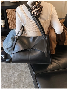 Dettaglio di una borsa a spalla in pelle nera con cuciture a pieghe e capienza elevata