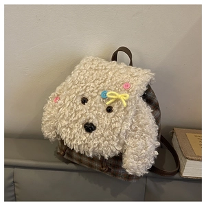 Dettaglio viso di cane in peluche con fiocco e tessuto a quadri retrò sul mini zainetto