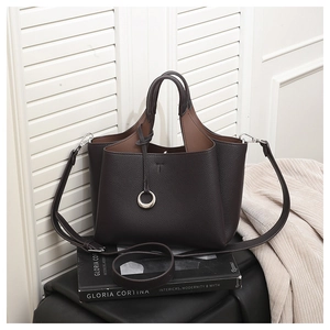 Detail of dark coffee litchi grain leather tote bag with metal ring and elegant book decor