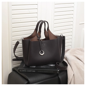 Detail of dark brown pebble leather tote bag with elegant folded side design and metal charm