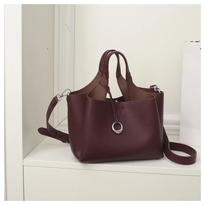 Detail of burgundy pebbled leather handbag featuring silver ring and crossbody strap