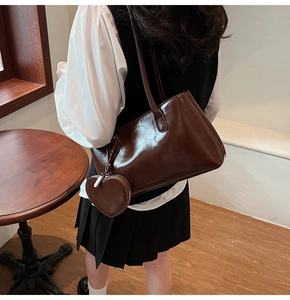 Close-up of deep brown glossy leather tote bag featuring a cute heart charm in a cafe