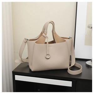 Detail view of beige lychee texture tote bag with silver ring pendant and strap