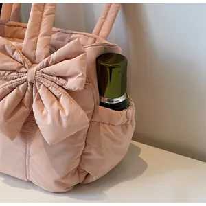 Detailed view of pink quilted tote bag with side pocket and decorative bow detail