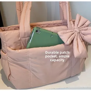 Detail of pink quilted tote bag showing large front pocket holding a green tablet device