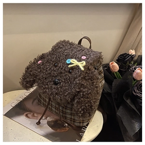 Dettaglio di un simpatico zaino in peluche a barboncino con tessuto scozzese e fiocco