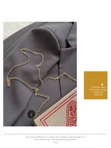 Détail de la bandoulière chaîne dorée et de la pochette de soirée à motif de cœur