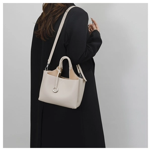 Detailed view of cream leather bucket bag with litchi texture and silver ring hardware