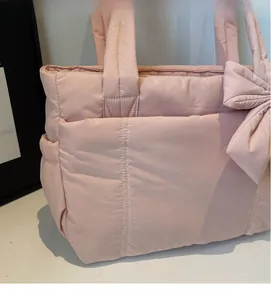 Close-up of pink quilted tote bag showing soft padded fabric and large decorative bow