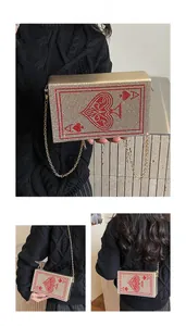 Close-up of golden clutch bag with red rhinestone Ace of Spades poker pattern and chain