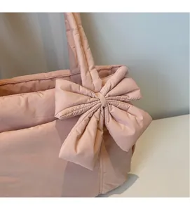 Detail of pink quilted puffer tote bag with a large decorative bow and soft padding