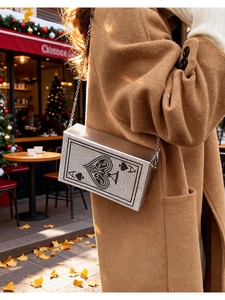 Détail du sac à chaîne argenté avec motif as de pique en strass sur un manteau brun