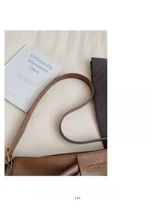 Close-up of brown leather tote bag with fashion text logo and adjustable shoulder strap