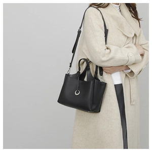 Detail of black pebbled leather bucket bag with silver ring accents and adjustable strap