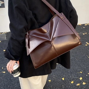 Borsa tote francese in pelle lucida marrone scuro indossata da una modella a spalla