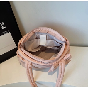 Detailed interior of a pink quilted tote bag showing lining and two inner pockets