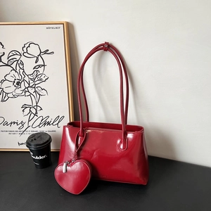Minimalist red patent leather tote bag with heart-shaped charm and long shoulder straps