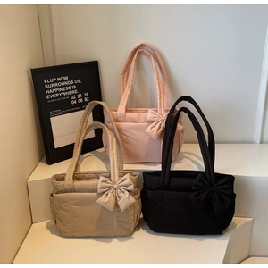 Detailed view of three quilted tote bags with large bows and side pockets in various colors