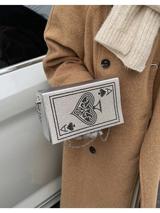 Detail of silver evening clutch with Ace of Spades rhinestone pattern on a camel coat