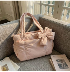 Macro detail of pink quilted tote bag with large decorative bow and soft padded texture