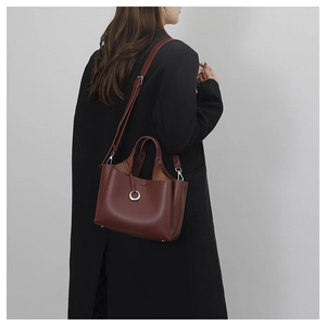Detailed view of burgundy pebble leather tote with silver ring on black wool coat