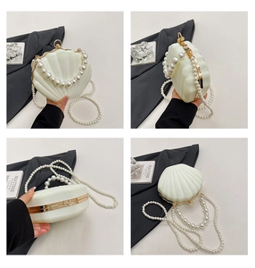 Detail of shell-shaped evening bag featuring glossy ivory finish and pearl handle strap