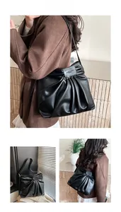 Detailed view of black pleated leather texture and rectangular logo on large hobo bag