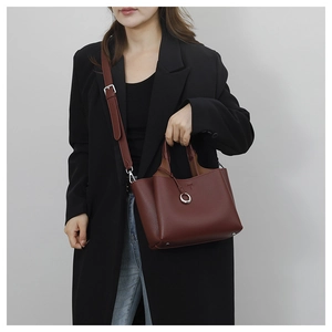 Detail of burgundy leather bucket bag with silver ring charm and embossed T logo