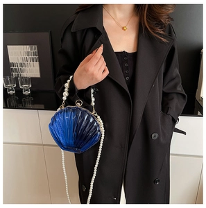 Detail of dark blue shell-shaped acrylic evening bag with pearl handle and chain