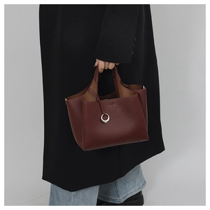 Dettaglio di una borsa in pelle bordeaux con trama litchi e anello in argento
