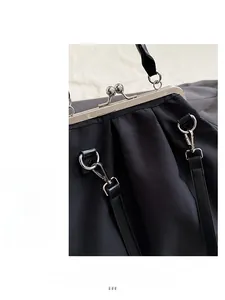 Détail du fermoir en métal argenté et du tissu noir brillant du sac à main fourre-tout