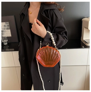 Detail of shell-shaped acrylic evening bag with pearl handle and crossbody chain