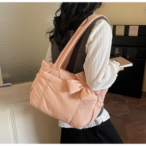 Detail view of pink puffy tote bag featuring a large decorative side bow and wide strap