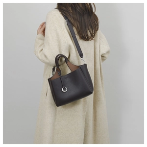 Detail of black lychee grain leather bucket bag with silver charm and brown lining