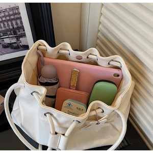 Spacious interior of a cream drawstring bucket bag filled with daily essentials