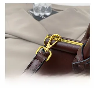Detail of high-quality gold metal hook and stitching on dark brown leather handbag