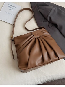 Detail of caramel brown pleated bucket bag with fashion leather tag and texture