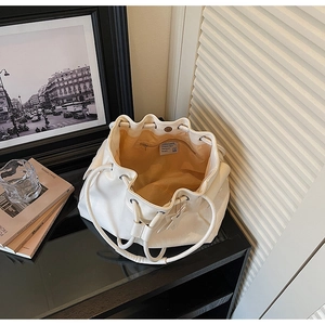 Top view of open white drawstring bucket bag showing spacious beige interior lining
